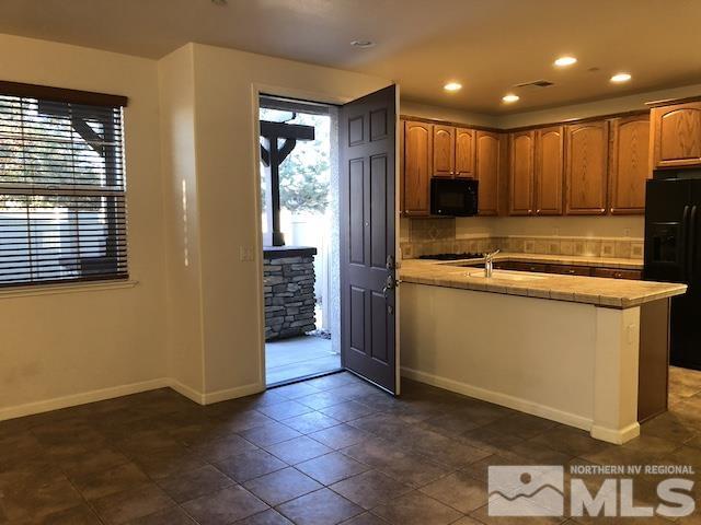 kitchen with dark tile patterned floors, black appliances, and kitchen peninsula