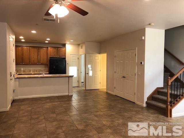 kitchen with a kitchen bar, kitchen peninsula, dark tile patterned floors, ceiling fan, and black fridge with ice dispenser