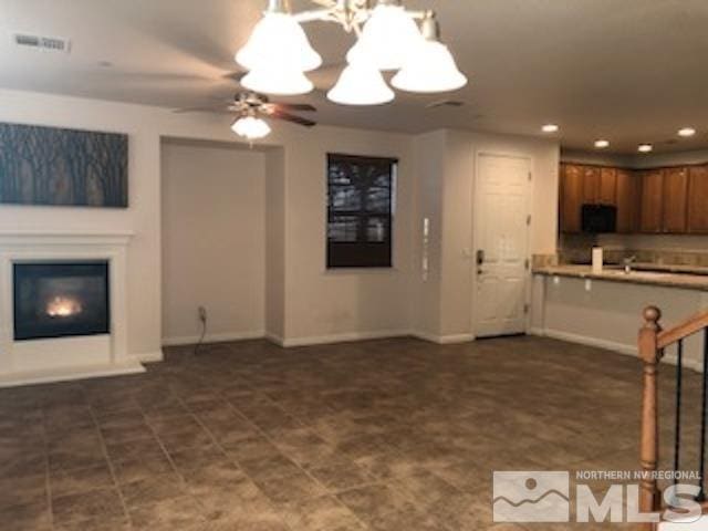 unfurnished living room with ceiling fan with notable chandelier