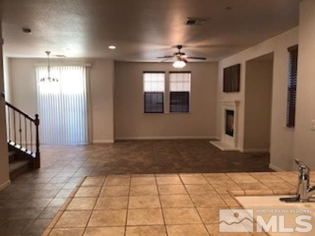 unfurnished living room with tile patterned floors and ceiling fan