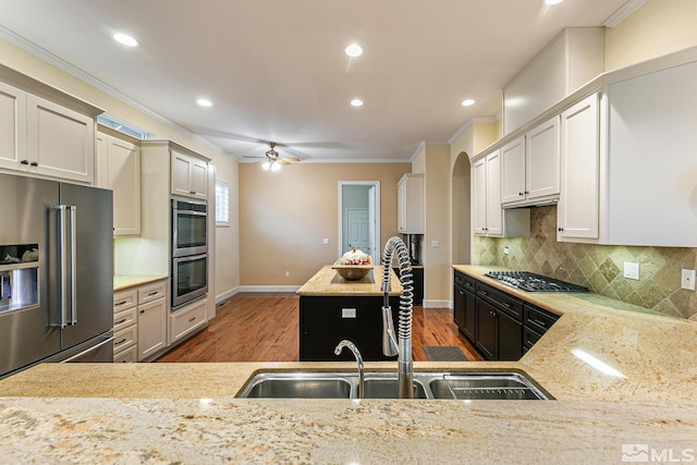 kitchen featuring light stone counters, sink, crown molding, and stainless steel appliances