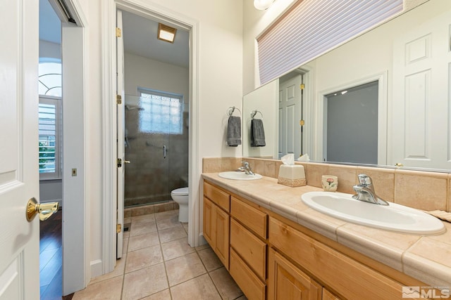 bathroom featuring a shower with door, vanity, tile patterned floors, and toilet