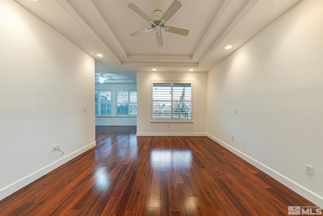 unfurnished room featuring ceiling fan, dark hardwood / wood-style flooring, and a raised ceiling