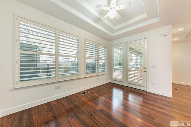 spare room with ceiling fan, dark hardwood / wood-style flooring, and a raised ceiling