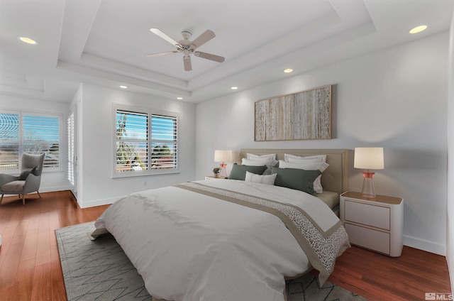 bedroom featuring dark hardwood / wood-style floors, a raised ceiling, and ceiling fan