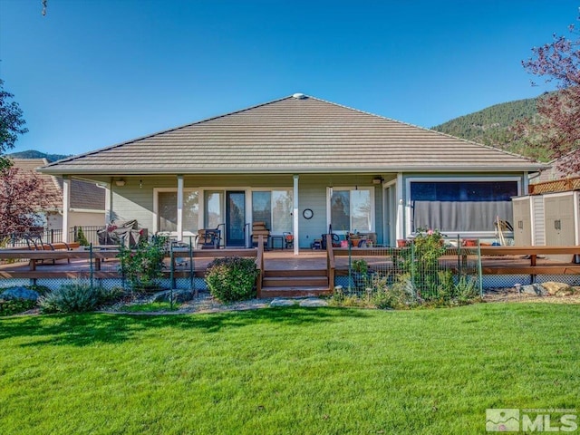 rear view of property featuring a lawn and a deck