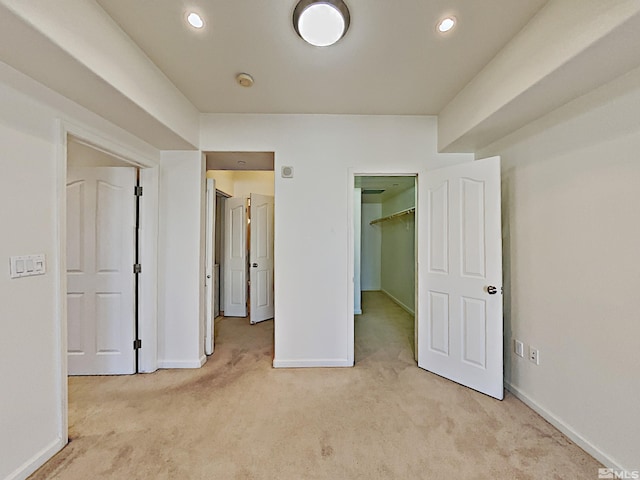 unfurnished bedroom featuring light colored carpet, a spacious closet, and a closet