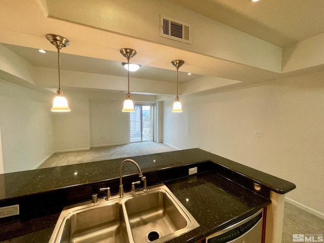 kitchen featuring dishwasher, sink, hanging light fixtures, dark stone counters, and light carpet