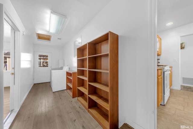 hall with light hardwood / wood-style flooring and independent washer and dryer