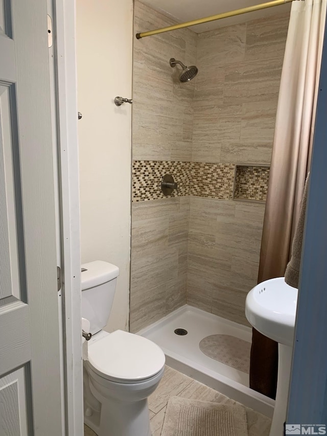 bathroom with toilet and a shower with shower curtain