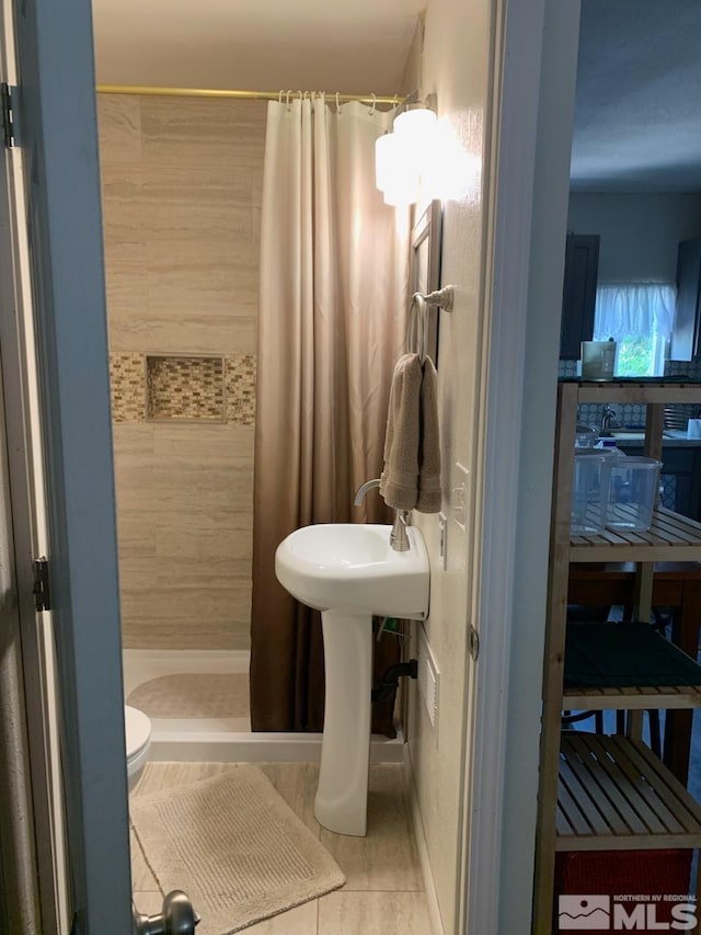 bathroom featuring toilet, tile patterned floors, and a shower with shower curtain