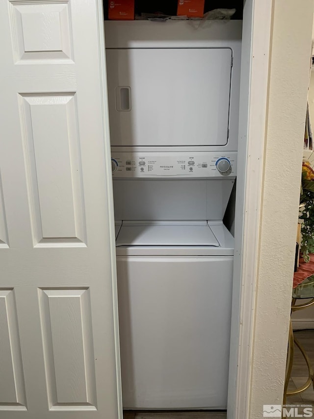 clothes washing area with stacked washer / dryer