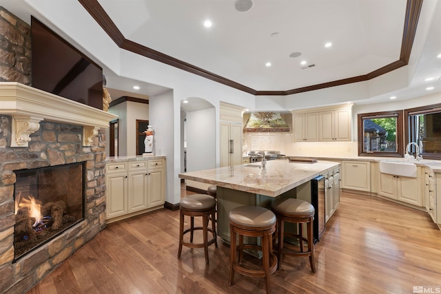 kitchen featuring sink, a kitchen bar, cream cabinetry, light hardwood / wood-style flooring, and a center island with sink