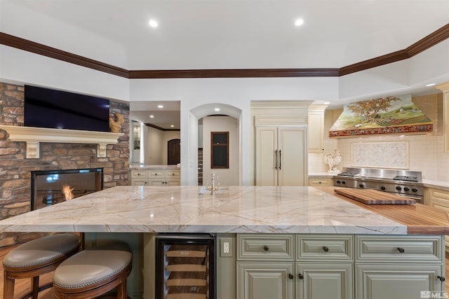 kitchen with a kitchen bar, a kitchen island, light stone counters, custom range hood, and wine cooler