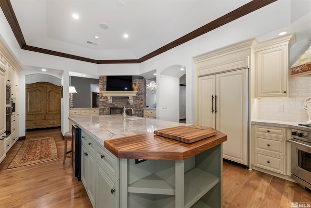 kitchen with cream cabinets, tasteful backsplash, light wood-type flooring, a center island, and butcher block countertops