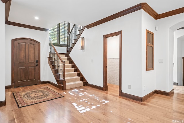 foyer with ornamental molding and light hardwood / wood-style floors