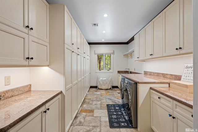 laundry room featuring cabinets, crown molding, sink, and washing machine and dryer