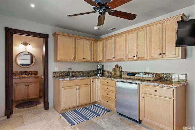 kitchen with ceiling fan, light brown cabinetry, dark stone counters, and stainless steel fridge