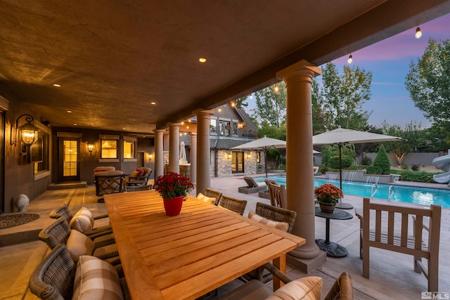 patio terrace at dusk with an outdoor living space and a fenced in pool