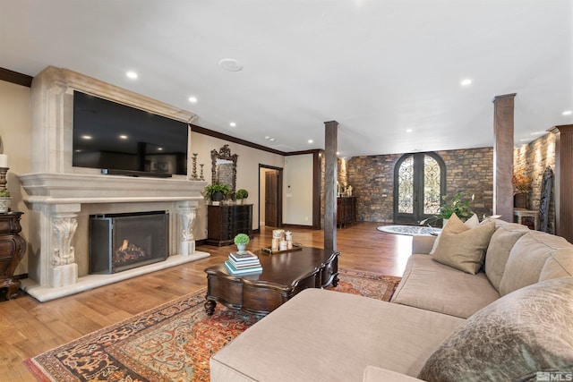 living room featuring ornate columns, crown molding, and wood-type flooring