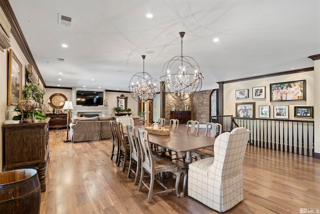 dining area with light hardwood / wood-style flooring, ornamental molding, and a chandelier