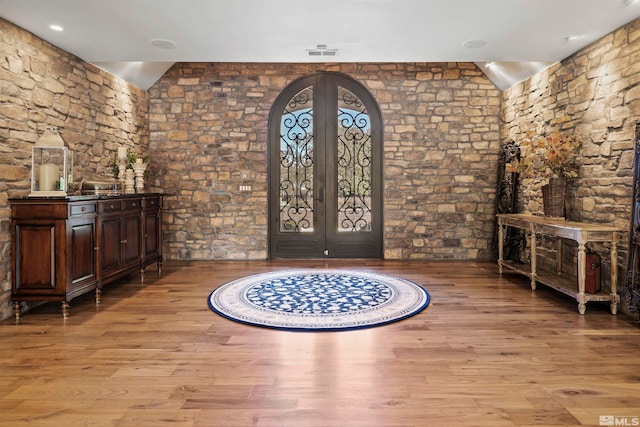 foyer entrance featuring light hardwood / wood-style flooring, french doors, and vaulted ceiling