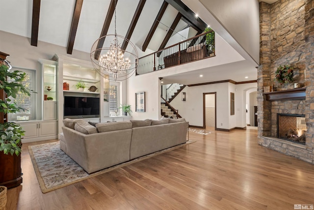 living room with light hardwood / wood-style floors, a stone fireplace, high vaulted ceiling, and beamed ceiling