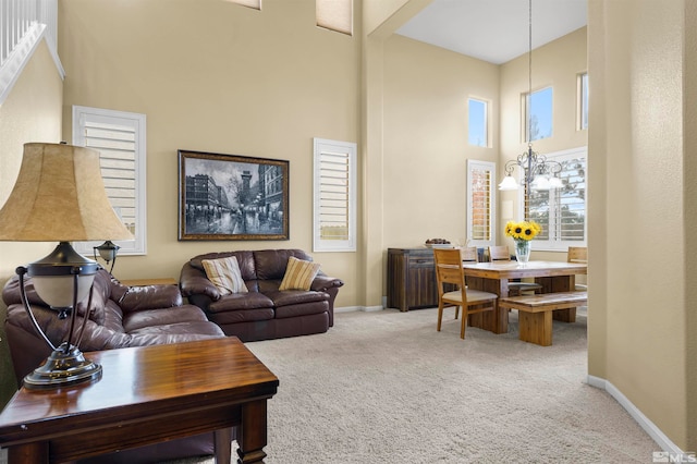 living room featuring a towering ceiling, an inviting chandelier, and carpet