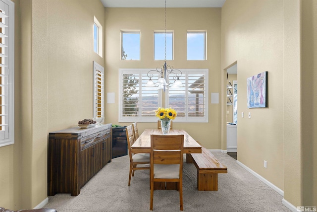 dining area with a high ceiling, light colored carpet, and an inviting chandelier