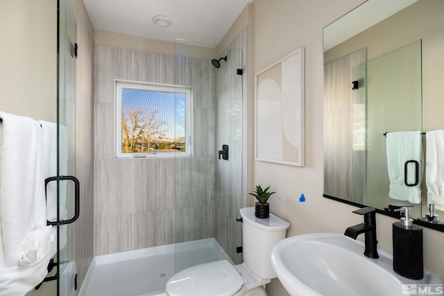 bathroom with a shower with door, sink, and toilet