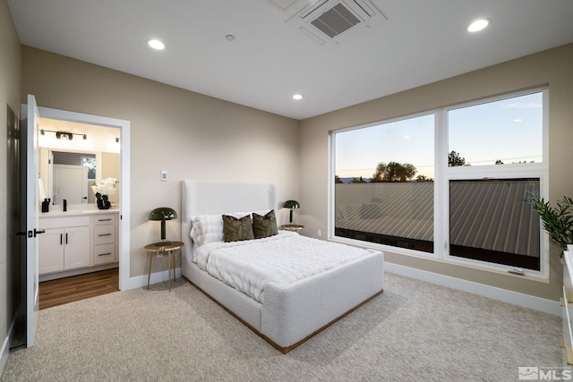 bedroom featuring connected bathroom, a fireplace, and light colored carpet