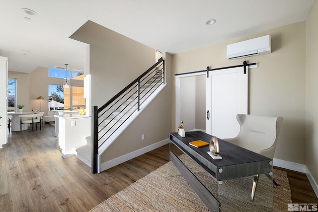 interior space with a wall unit AC, light hardwood / wood-style floors, and a barn door