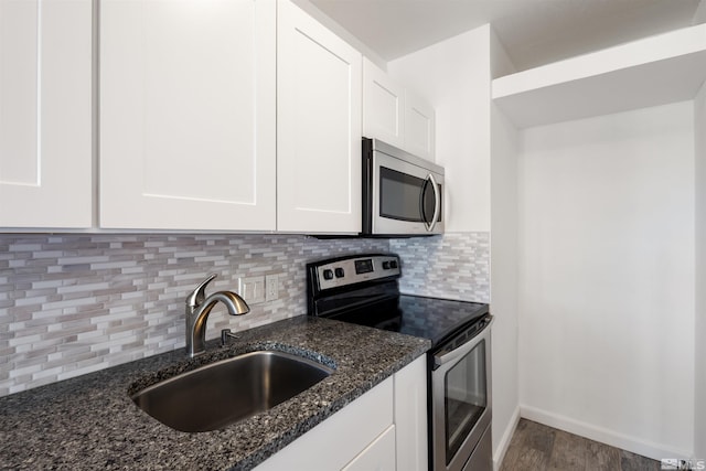 kitchen with stainless steel appliances, backsplash, dark stone counters, white cabinets, and sink