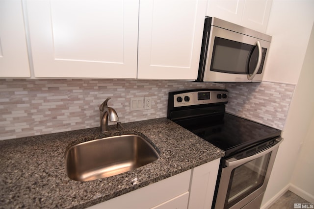 kitchen featuring dark stone countertops, decorative backsplash, sink, white cabinetry, and stainless steel appliances