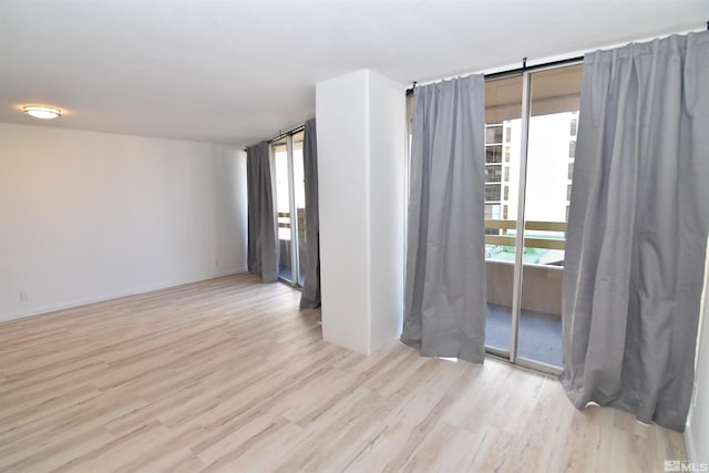 empty room featuring expansive windows and light hardwood / wood-style floors