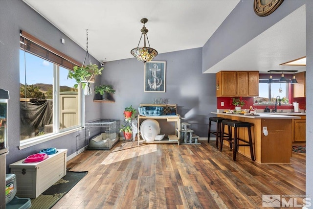 interior space with a breakfast bar, dark hardwood / wood-style floors, hanging light fixtures, and kitchen peninsula