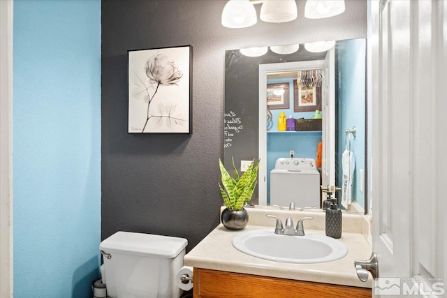 bathroom with vanity, toilet, and washer / clothes dryer