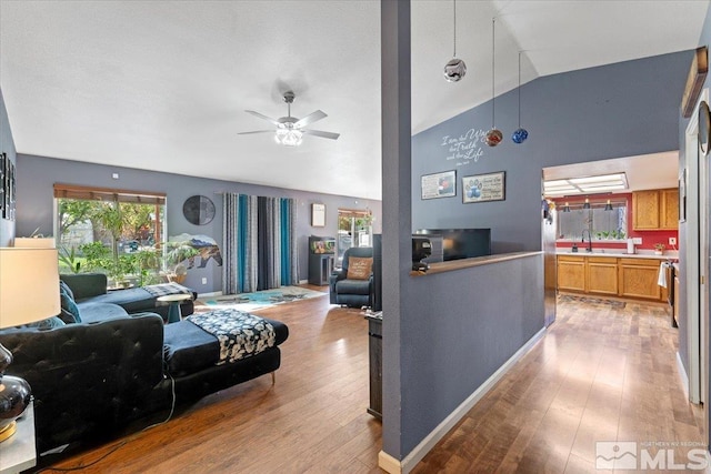 living room featuring light hardwood / wood-style flooring, sink, high vaulted ceiling, and ceiling fan