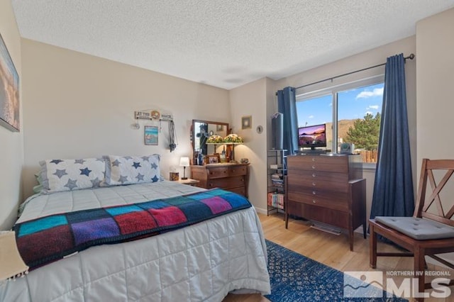 bedroom with a textured ceiling and light wood-type flooring