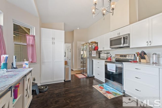 kitchen with appliances with stainless steel finishes, white cabinetry, vaulted ceiling, and dark hardwood / wood-style floors