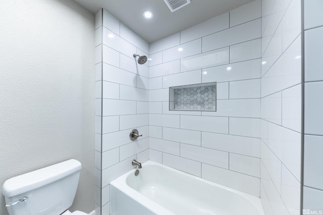 bathroom featuring toilet and tiled shower / bath combo