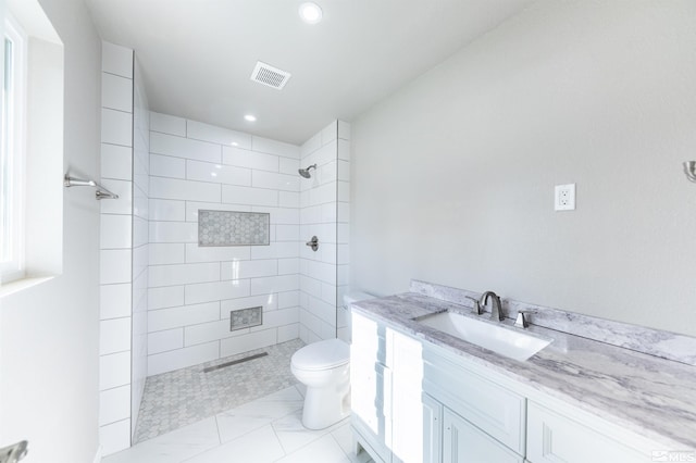 bathroom featuring vanity, toilet, and tiled shower