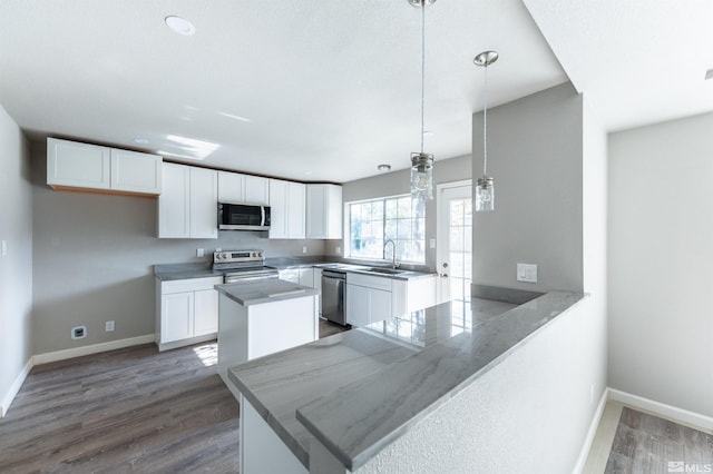 kitchen featuring appliances with stainless steel finishes, kitchen peninsula, white cabinets, and hanging light fixtures