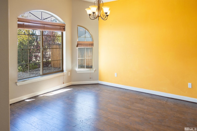 spare room with dark wood-type flooring and a chandelier