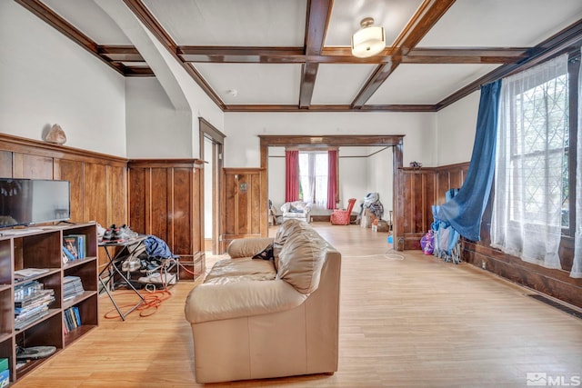 living room featuring light hardwood / wood-style floors, beam ceiling, wooden walls, and coffered ceiling