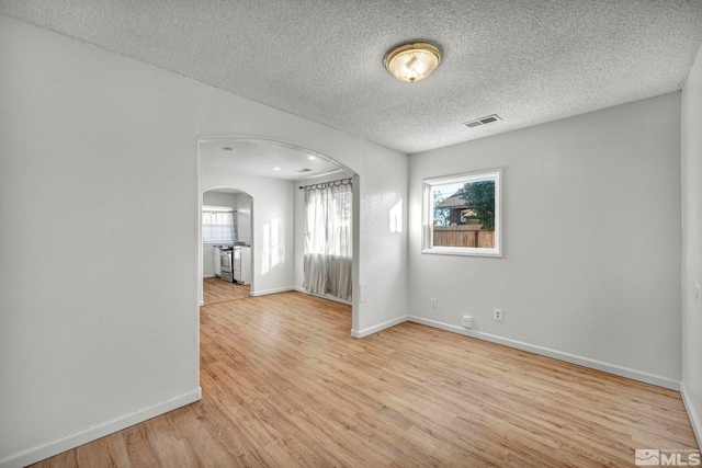 unfurnished room featuring a textured ceiling and light wood-type flooring