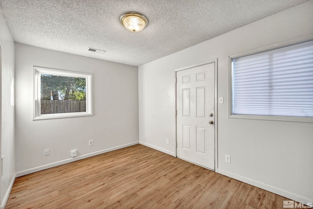 spare room featuring light hardwood / wood-style floors and a textured ceiling