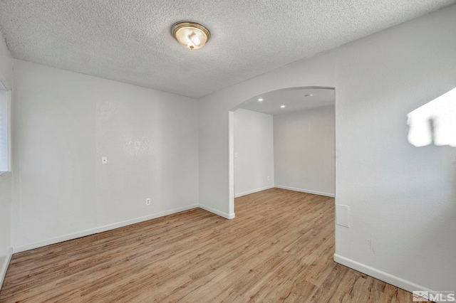 spare room with a textured ceiling and light hardwood / wood-style floors