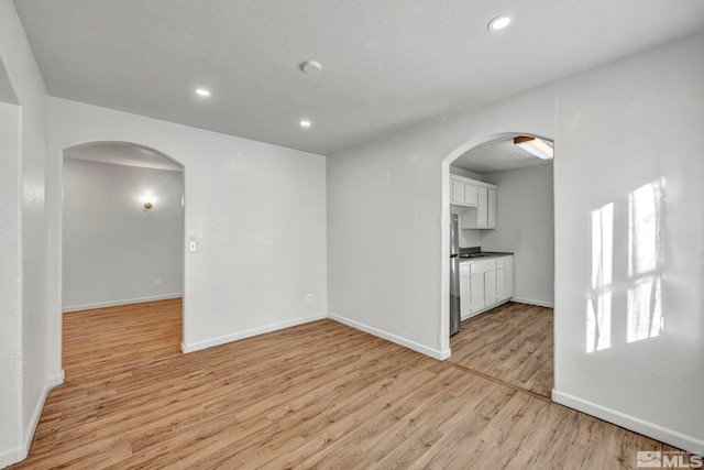 unfurnished living room featuring light hardwood / wood-style floors and a textured ceiling