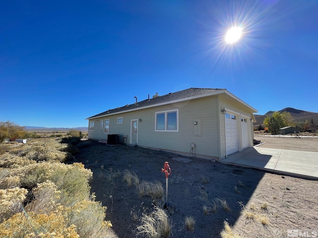 rear view of house with a garage, a mountain view, and central AC unit